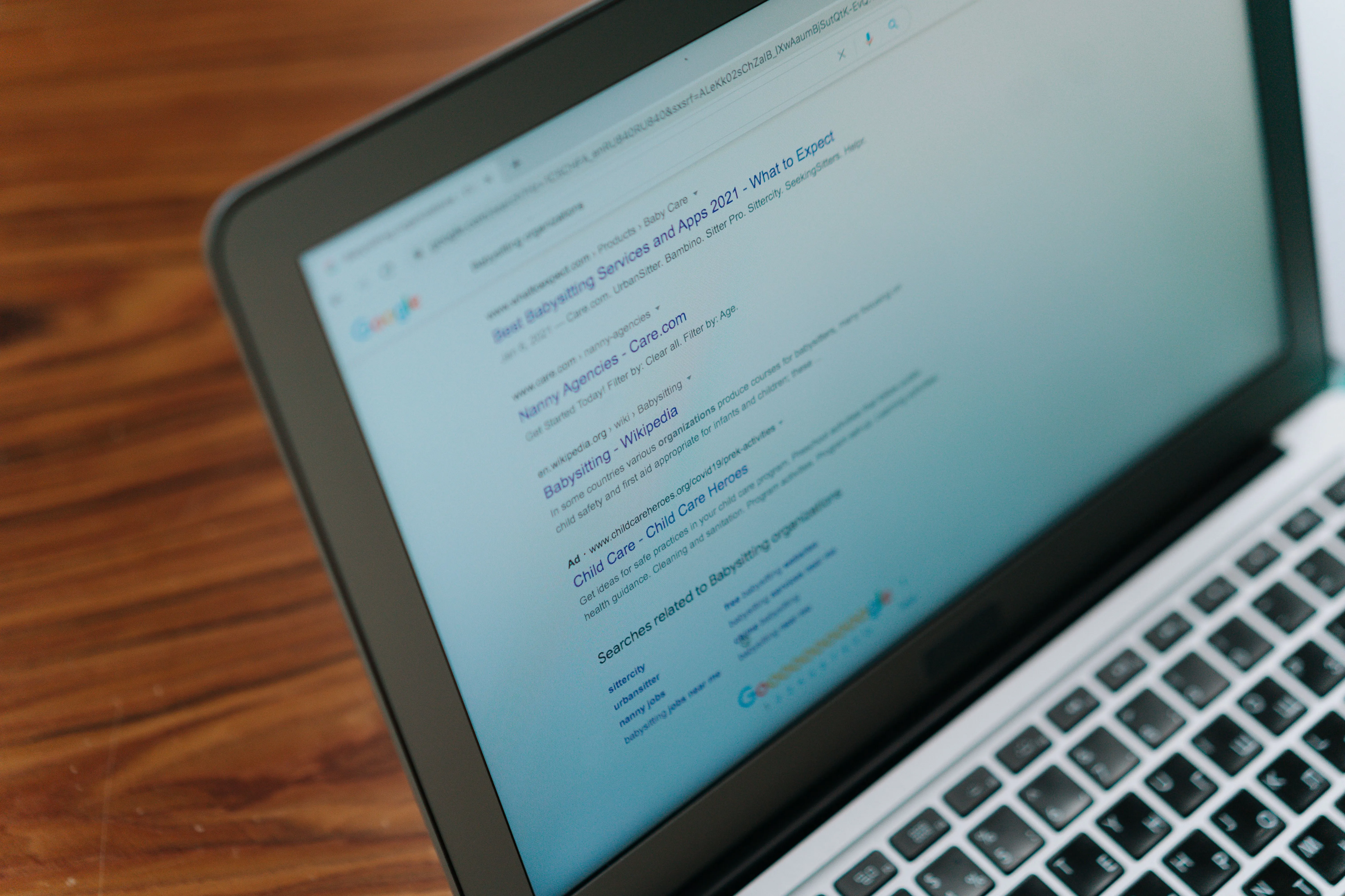 Blurred Google search engine results page open on a laptop screen, representing organic search results below an AI Overview
